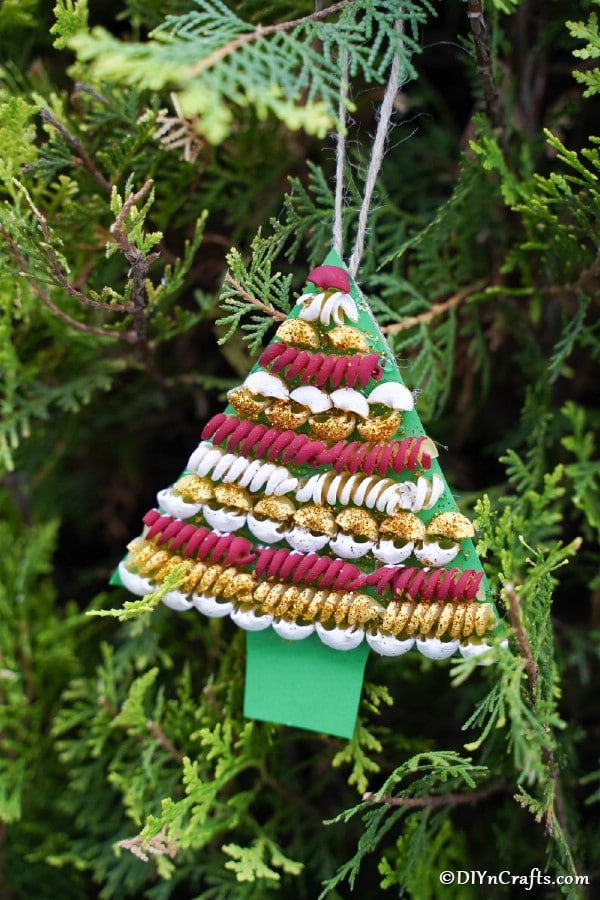 A pasta tree christmas decoration hanging on a green holiday tree