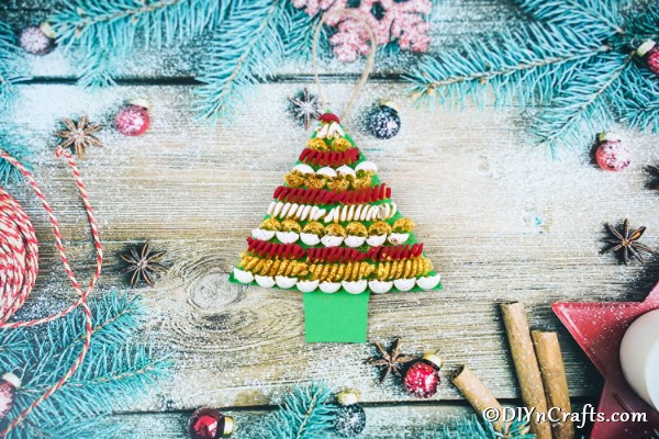A completed pasta tree christmas decoration on a wooden table surrounded by blue garland