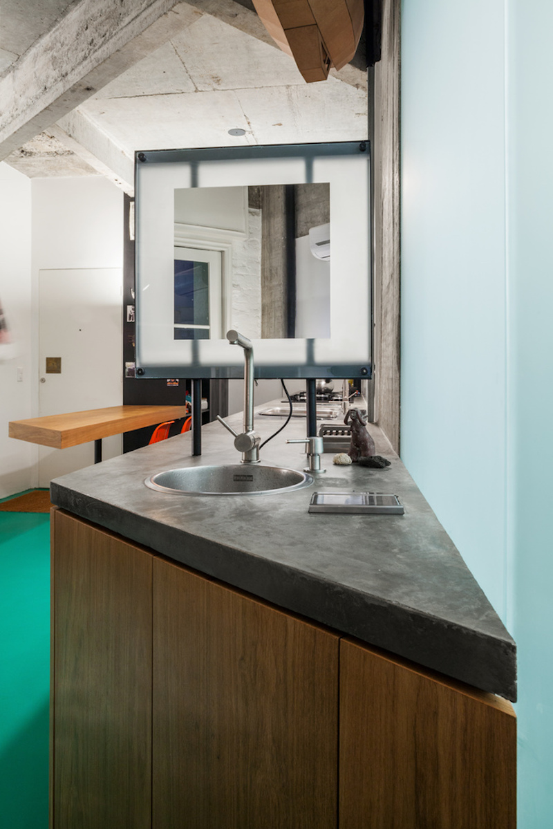 The concrete countertop adds a subtle industrial touch to the kitchen and shares a strong connection with the kitchen