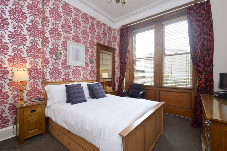 Удобная кровать для гостей в комнате с красивыми обоями