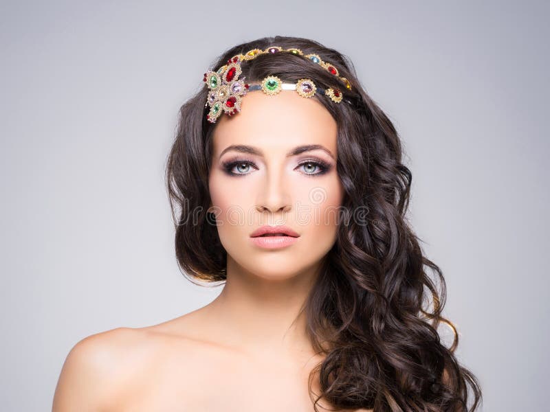 Attractive, curly brunette with a flower golden headband stock photography