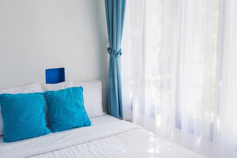 Blue theme pillows white bedroom light curtain. Light blue theme pillows white mattress bedroom light through curtain royalty free stock image