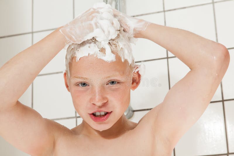 Boy washing his hair in the shower. Young boy washing his hair in the shower using a lot of soap stock image