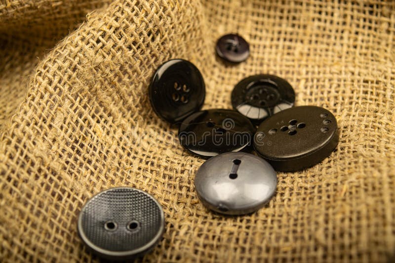 Buttons of different sizes on burlap with a rough texture. Close up.  stock photography