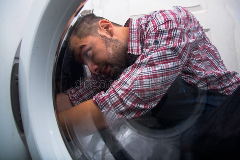 HANDYMAN REPAIRING WASHING MACHINE IN BATHROOM stock image