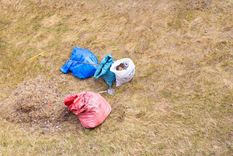 Cleaning the yard with a rake, on the ground are bags of garbage and leaves. Kogalym, Russia - 05.04.2020:cleaning the yard with a rake, on the ground are bags royalty free stock photos