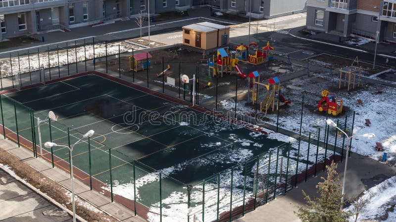 Empty sports basketball and football ground and deserted children`s playground in the yard of a residential building with empty. Sidewalks on a sunny day during stock images