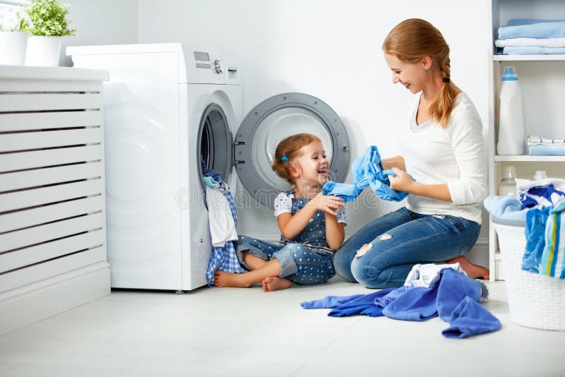 Family mother and child girl little helper in laundry room near washing machine. And dirty clothes stock image