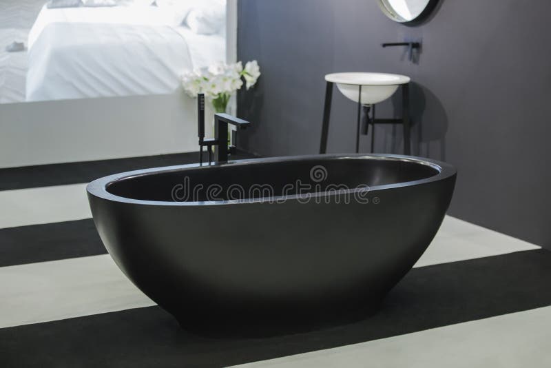Freestanding black bathtub, stylish minimalist black and white loft style bathroom. Bath, washstand, mirror on the wall royalty free stock images