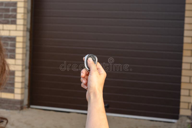 Hand with remote control opens sectional garage door stock images