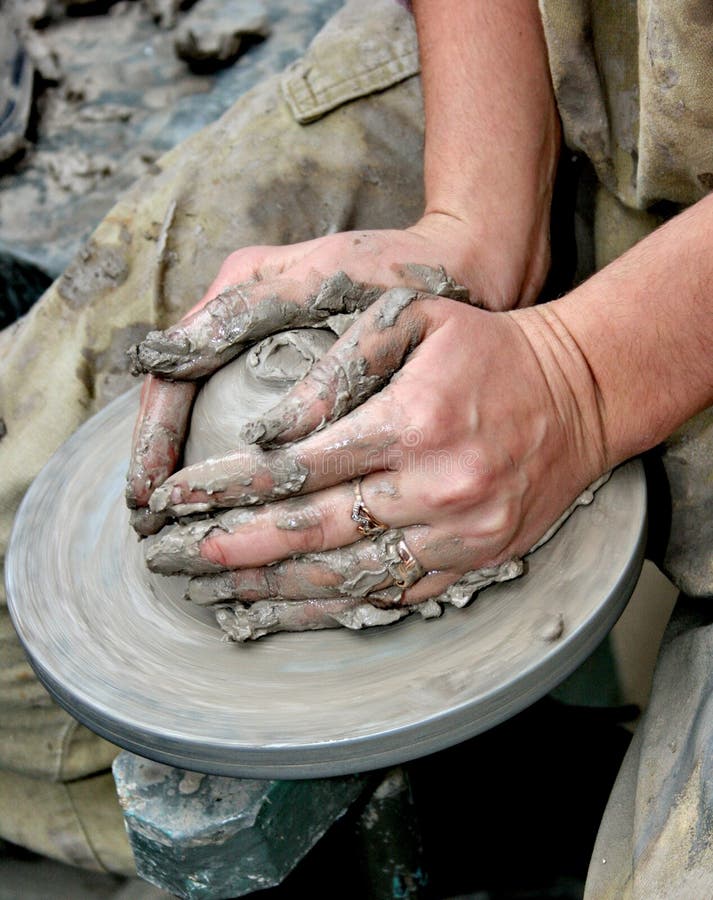 Hands shaping clay on potter