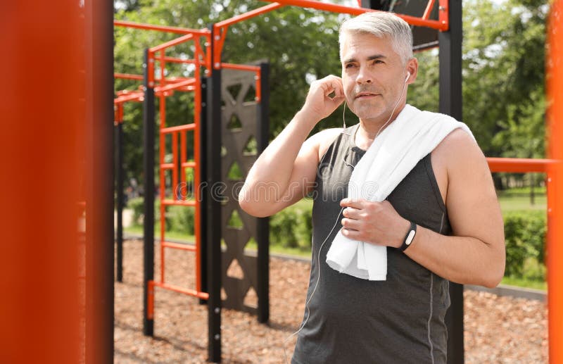 Handsome mature man listening to music on sports ground. Healthy lifestyle stock images