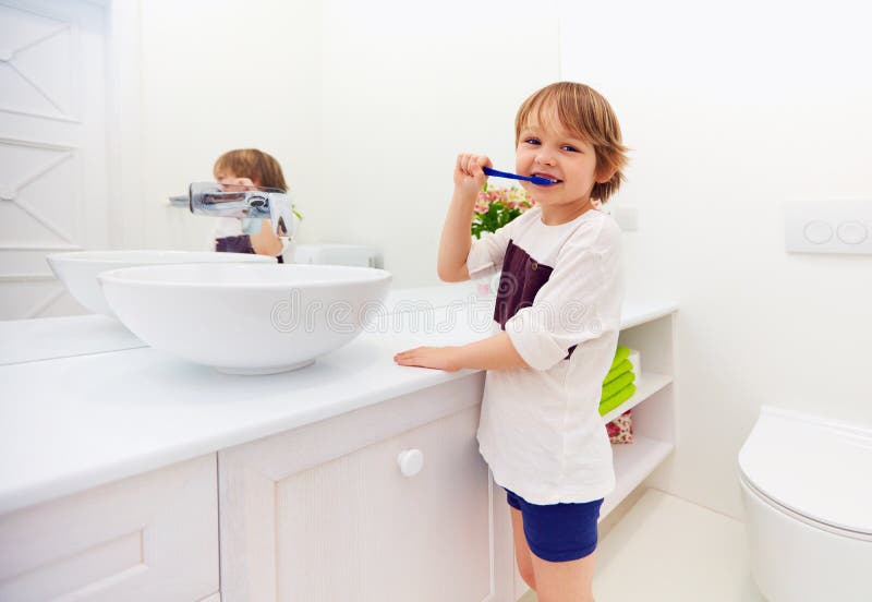 Happy young boy brushing teeth in bathroom stock images