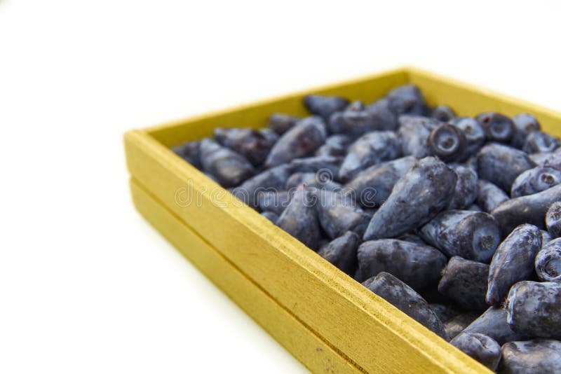 Honeysuckle blue berry fruits in a box. Honeysuckle blue berry fruits in a wood box on white background close up stock photography