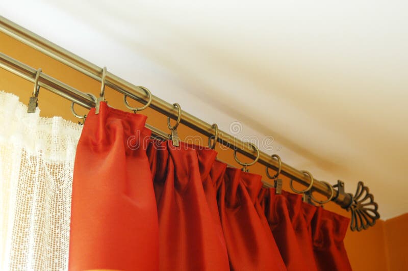 Living room window treatment. A view of curtain rods and red curtains or drapes hung as window treatment for a living room window royalty free stock image