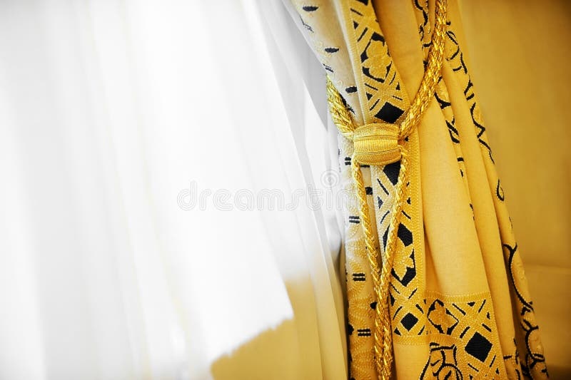 Luxury window curtain. Luxury yellow window curtain with decorative tassel stock photography