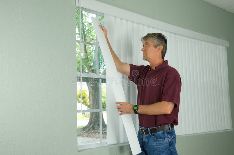 Man hanging vertical blinds home repair maintenance. A handy man home repair service technician or home owner hanging white vertical blinds for the window royalty free stock photography