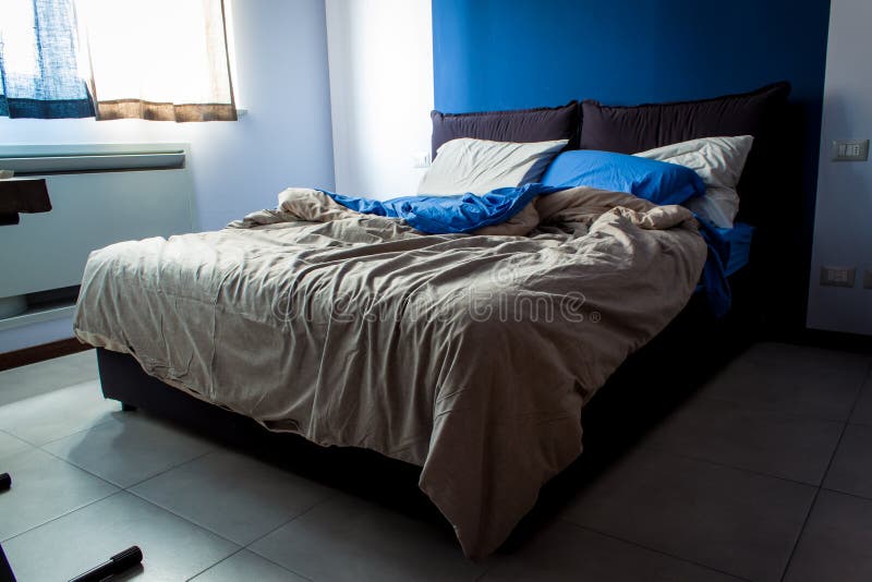 Messy bedroom sheets. A little bedroom, light bedsheets, the main color is blue stock photos