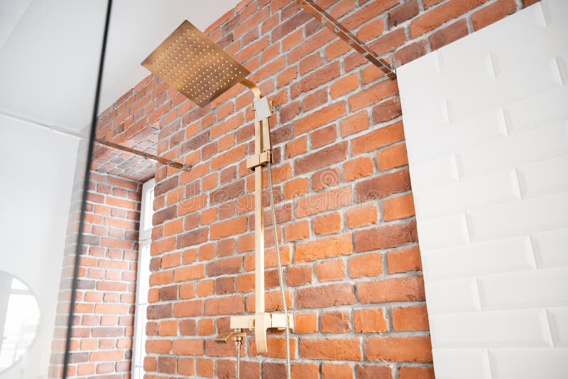 Modern shower system copper color for bathroom in loft style, brick wall. Sunlight window stock image