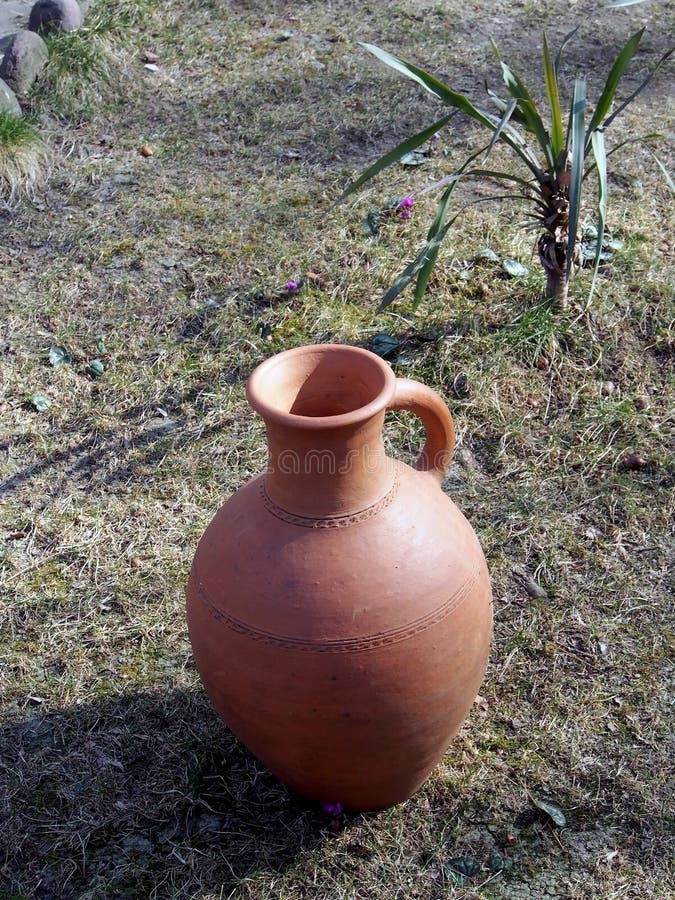 Old jug on the ground in the yard of a roadside restaurant. Old clay jug on the ground in the yard of a roadside restaurant, performs decorative functions royalty free stock photos
