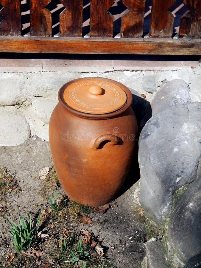 Old jug on the ground in the yard of a roadside restaurant. Old clay jug on the ground in the yard of a roadside restaurant, performs decorative functions stock photo