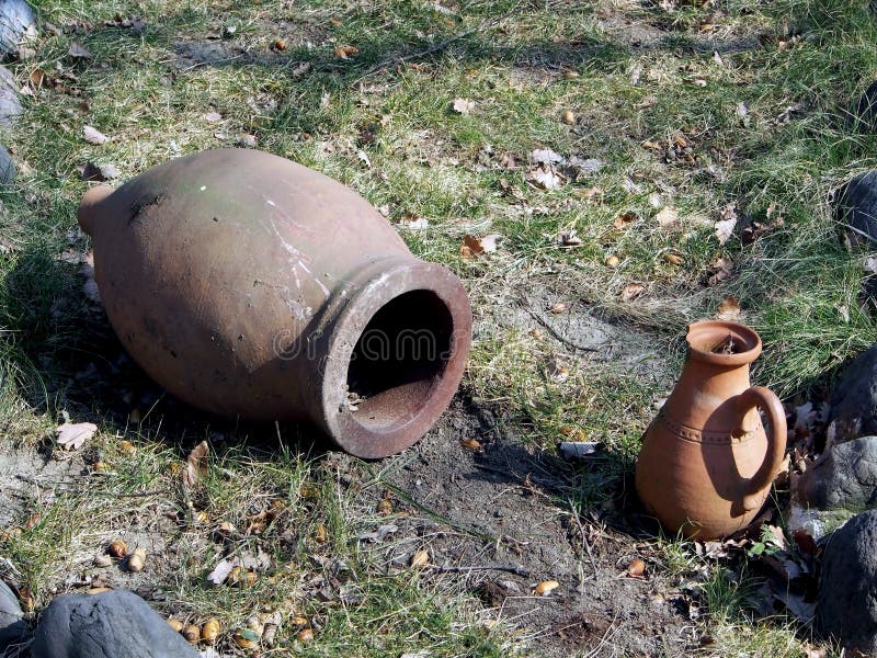 Old jug on the ground in the yard of a roadside restaurant. Old clay jug on the ground in the yard of a roadside restaurant, performs decorative functions stock image