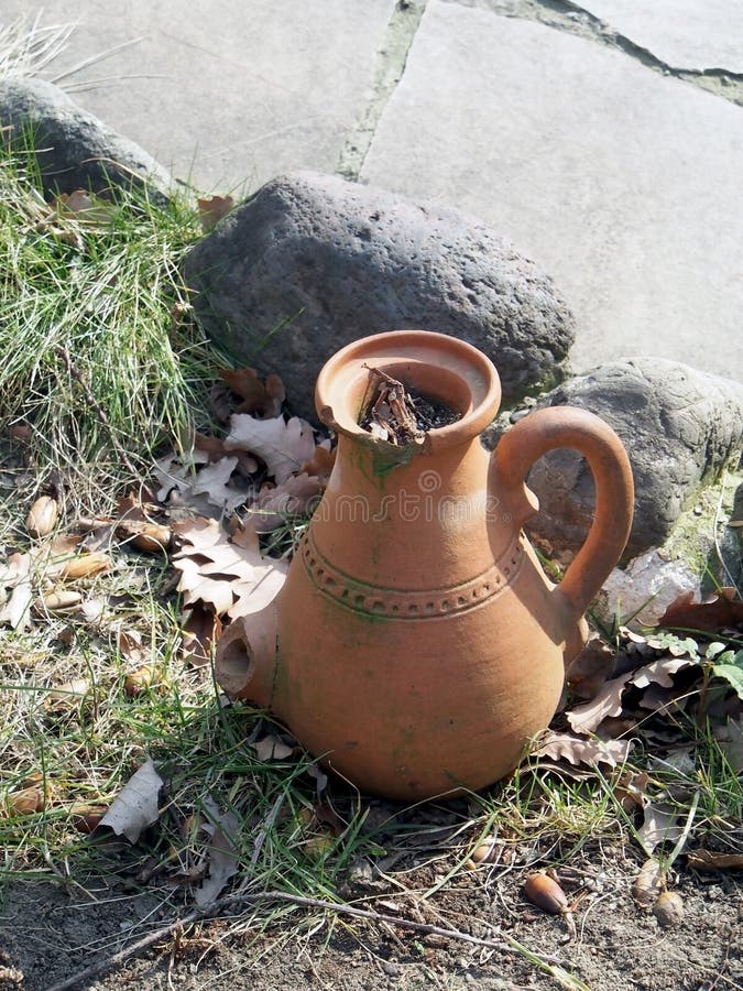 Old jug on the ground in the yard of a roadside restaurant. Old clay jug on the ground in the yard of a roadside restaurant, performs decorative functions royalty free stock photos