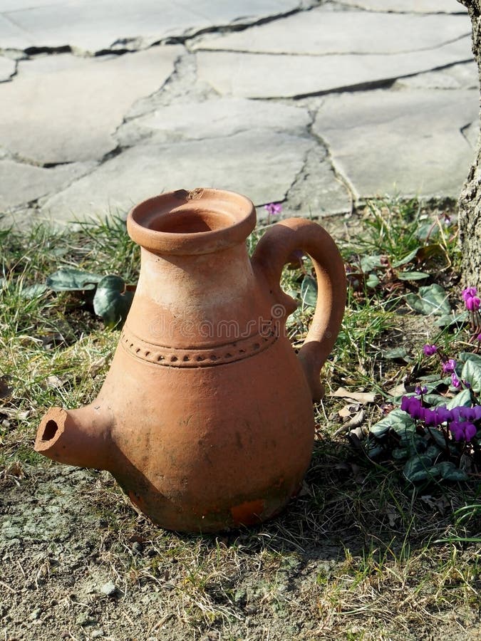 Old jug on the ground in the yard of a roadside restaurant. Old clay jug on the ground in the yard of a roadside restaurant, performs decorative functions stock images