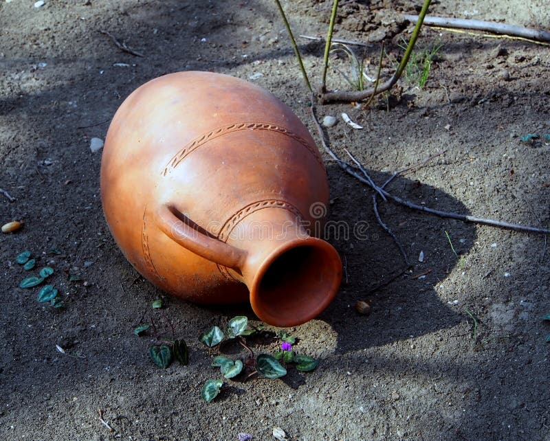 Old jug on the ground in the yard of a roadside restaurant. Old clay jug on the ground in the yard of a roadside restaurant, performs decorative functions stock image