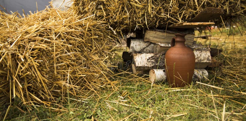 Old traditional clay vase on a ground of fence village yard surrounded by stack of hay. Old traditional clay vase on a ground of fence village yard surrounded by royalty free stock photos