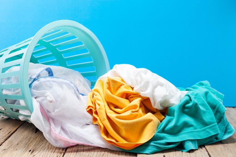 Pile of dirty laundry in washing basket on wooden,blue background. stock image