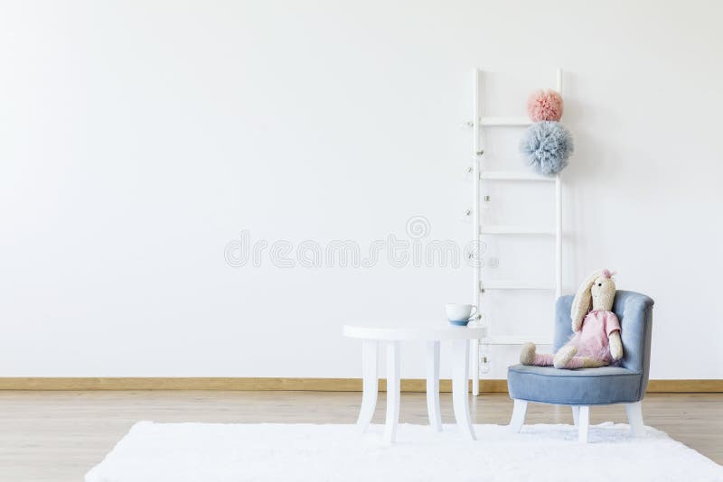 Plush toy on grey chair at white table in minimal child`s room i. Nterior with copy space. Real photo stock images