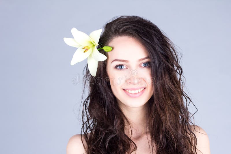 Pretty woman with curly brown hair and a flower in her hair smiling with teeth royalty free stock photos