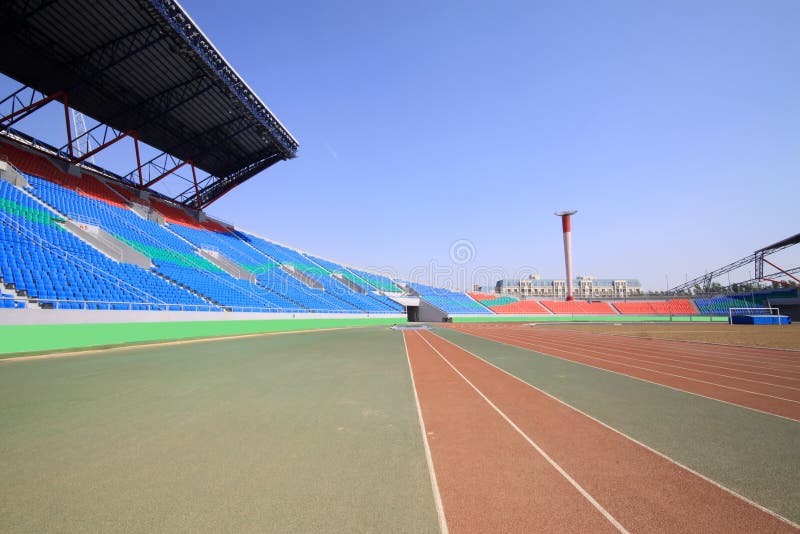 Red plastic runway and building in a sports ground royalty free stock photography