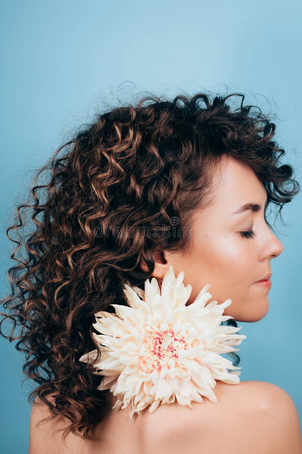 Sensuality young curly woman is holding in her mouth white chrysanthemum flower. royalty free stock photo