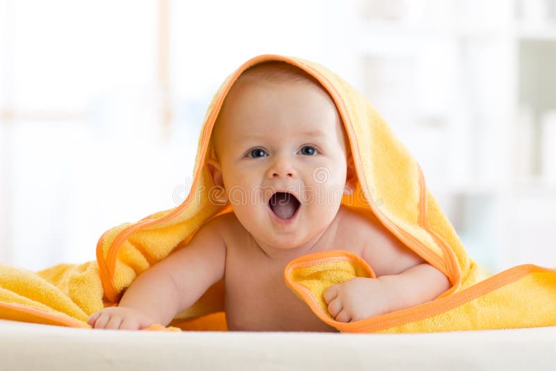 Smiling baby under soft towel. Cute child lying on bed after bathing in living room. Smiling baby covered soft towel. Cute child lying on bed after bathing or stock images