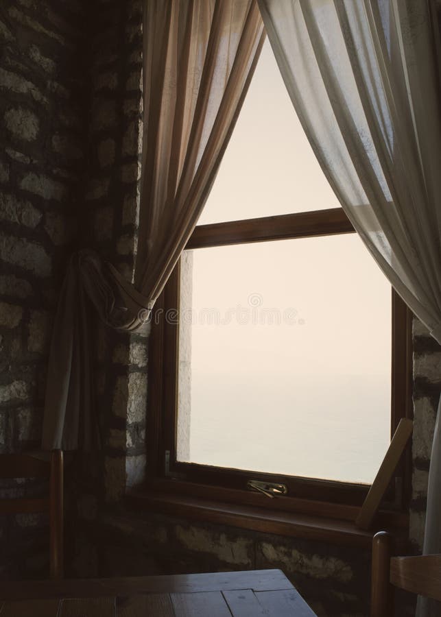 Soft light seeping in from a window. Soft light seeping in from a window partly covered by thin curtains. Chairs and a table in front of the window royalty free stock images
