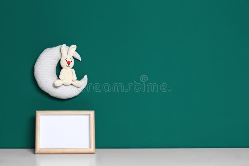 Soft toys and photo frame on table against green, space for text. Child room interior. Soft toys and photo frame on table against green background, space for stock photos