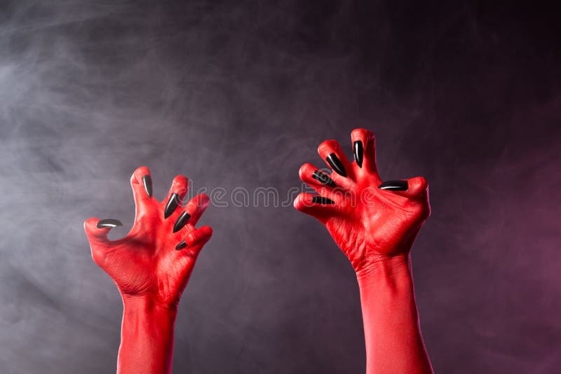 Spooky red devil hands with black glossy nails stock photo