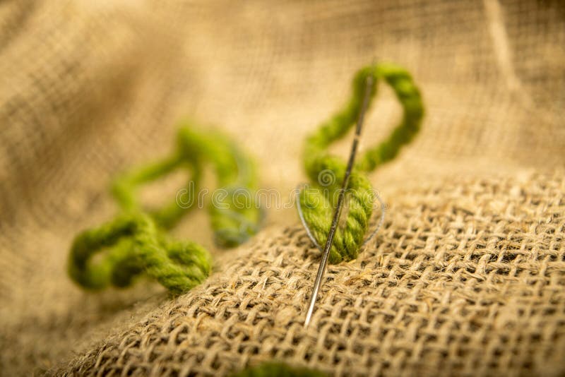 Stitches of green thread on the burlap with a rough texture. Close up.  stock images