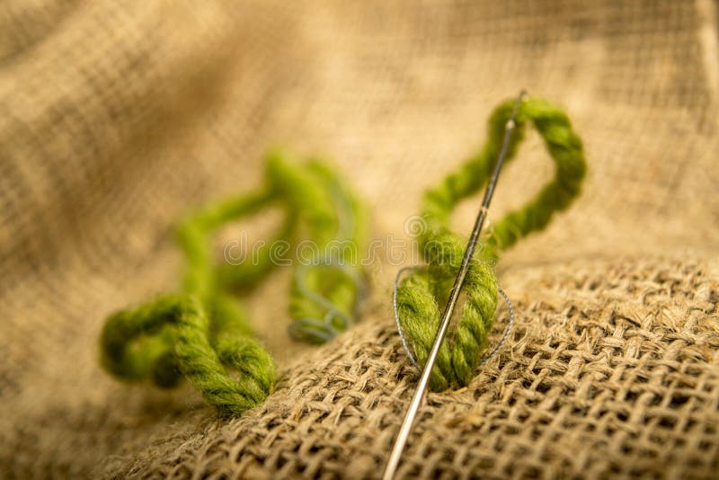Stitches of green thread on the burlap with a rough texture. Close up.  stock images