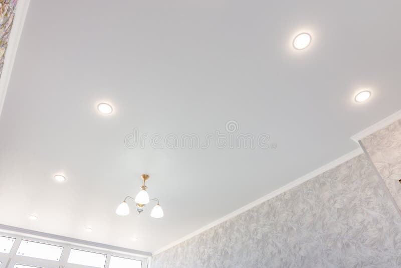 Stretch ceiling in the room with a chandelier and spotlights stock photography