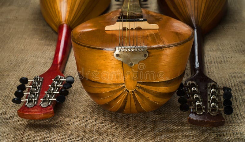 Three old mandolins rotated fingerboards to the camera on a background of rough burlap texture. Selective focus royalty free stock photo