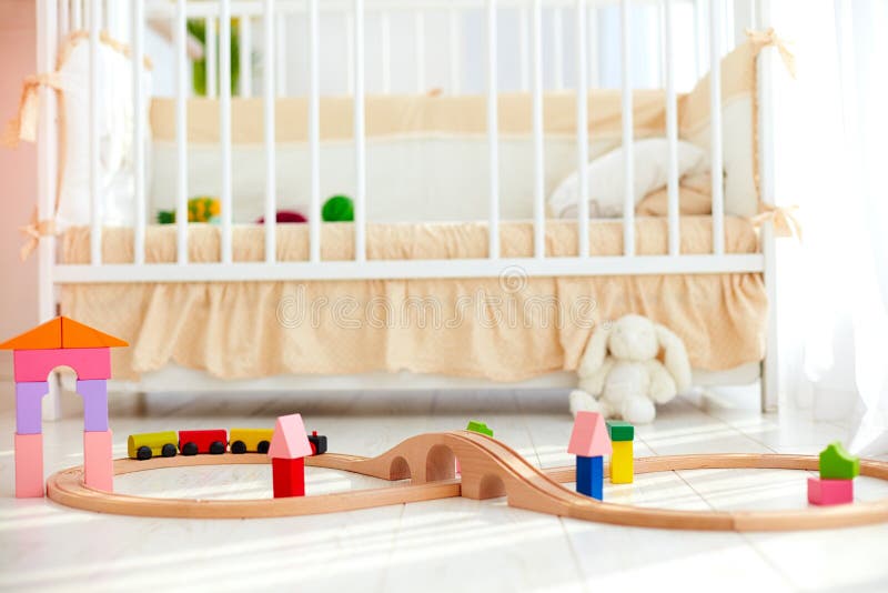 Toys on the floor in sunny baby bedroom with crib on background. Toys on the floor in sunny baby bedroom with a crib on background royalty free stock photos