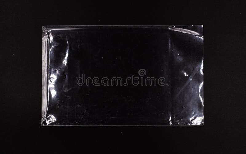 Transparent sealed plastic envelope on a black background, disposable glossy polyethylene bag stock image