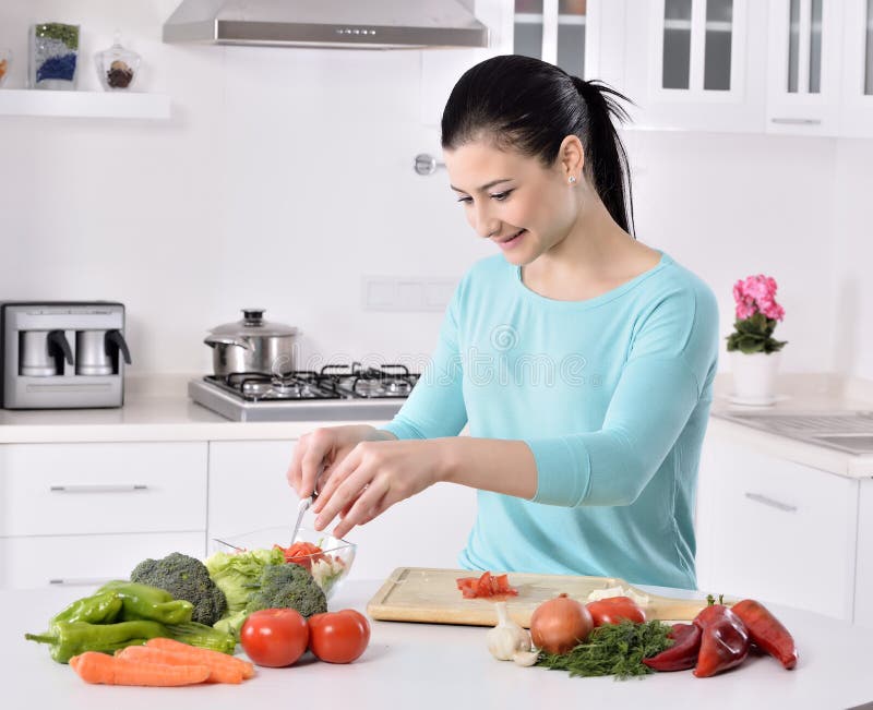 Woman cooking in new kitchen making healthy food with vegetables. royalty free stock images
