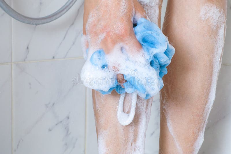 Woman with sponge washing legs in shower bath. Woman in  foam with sponge washing legs in shower bath royalty free stock photo