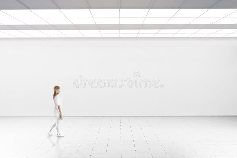 Woman walk in museum gallery with blank wall. Empty big hall wall mockup. Woman walk in museum gallery with blank wall. White clear stand mock up lobby. Display royalty free stock images