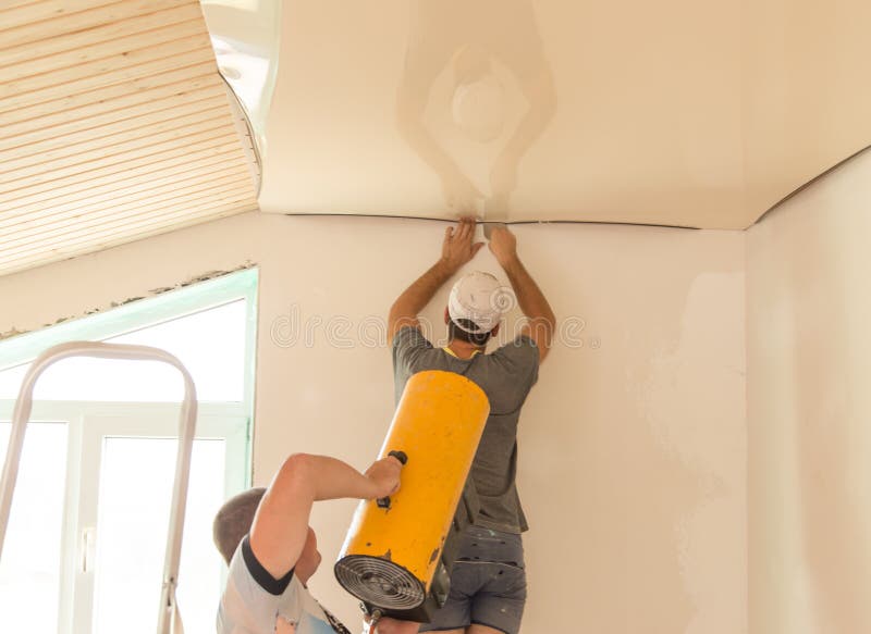 Workers stretch the stretch ceiling in the room stock photo