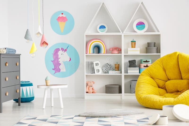 Yellow pouf in colorful child`s room interior with lamps and pos. Ters stock image
